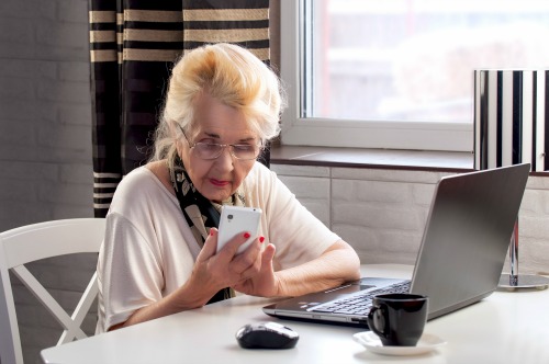 elderly lady talking on the phone and woking with computer